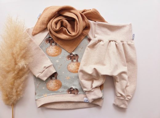 Beige Oberteil mit Tiermotiven, beiger Schal und Hose in neutralem Farbton.