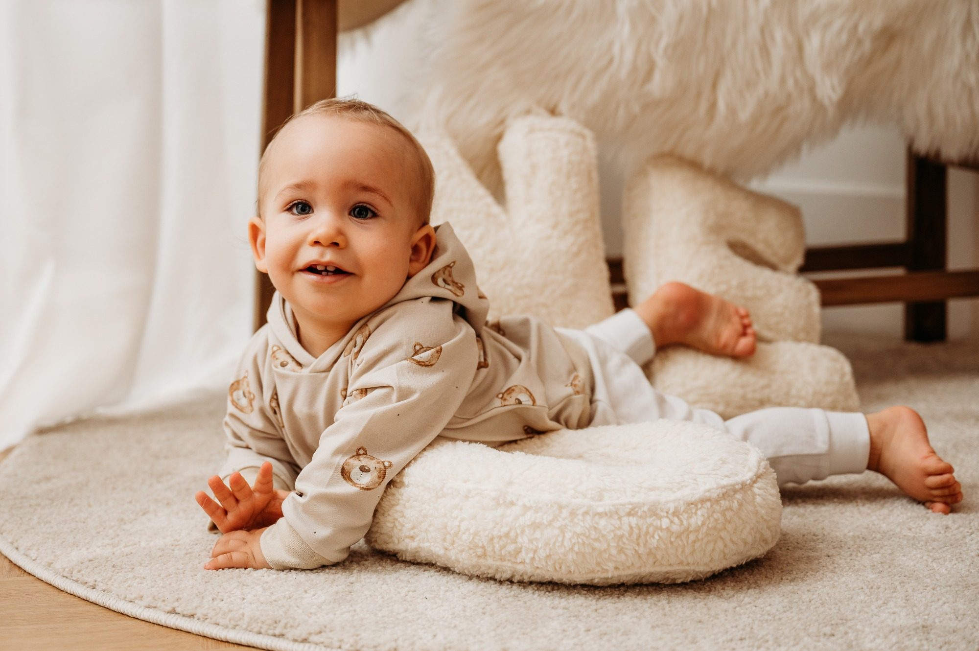 Ein Kind mit rotem Hut spielt mit Geschenken auf dem Boden in einer festlichen Umgebung.